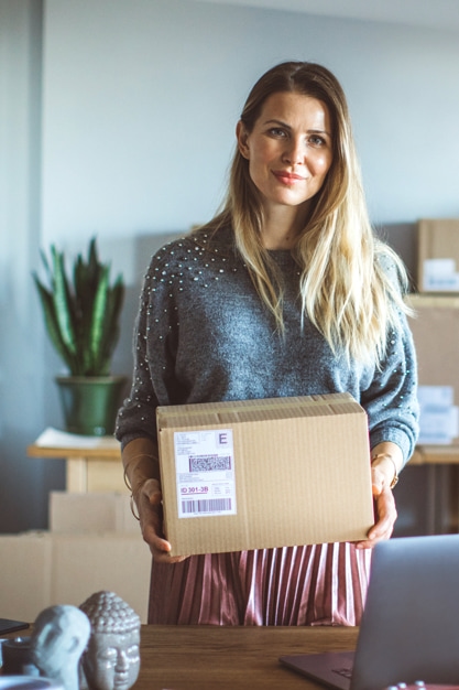 Woman holding a packet in her hands; Online store order ready to send to customer
